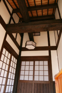 玄関ホール：あえて構造を見せ、高く吹き抜け、迫力のある玄関ホール。100年以上も前の松の古材を梁として使用しています。